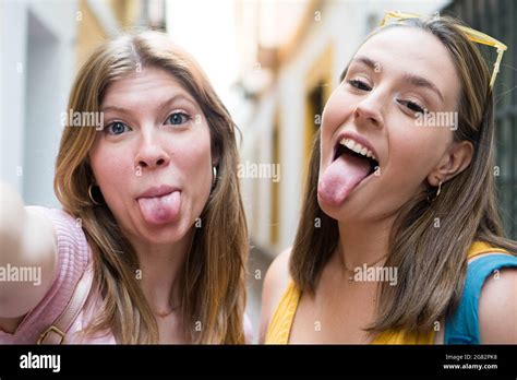 Two Young Friends Taking A Photo And Sticking Their Tongues Out At The