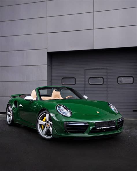 A Green Porsche Sports Car Parked In Front Of A Garage With Its Doors