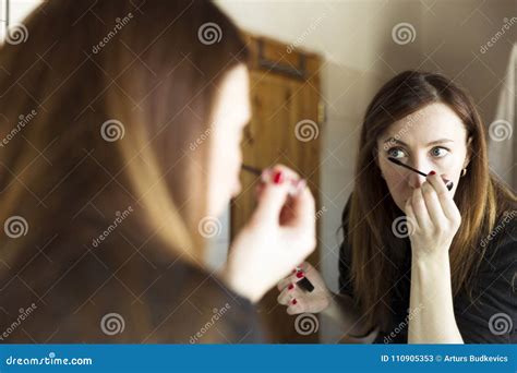 Woman Applying Black Mascara On Eyelashes With Makeup Brush In Bathroom