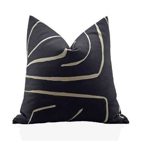 A Black And White Pillow With Gold Lines On The Front Sitting On A