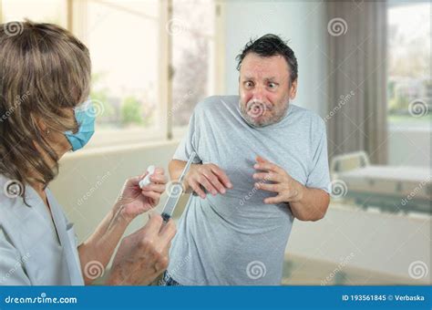 Man Is Deadly Scared Of A Syringe With A Needle In Hospital Stock Image