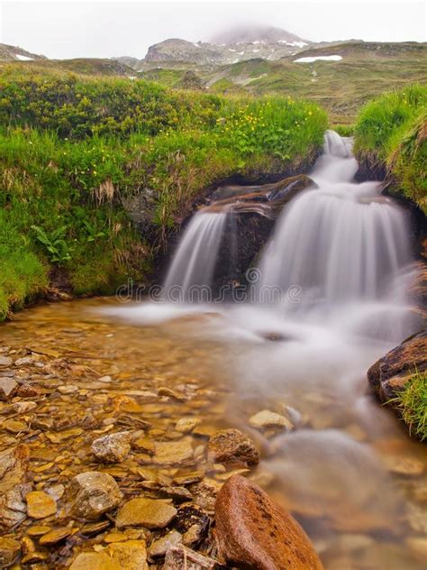 Small Waterfall On Mountain Stream In Summer Meadow Of Alps Cold And