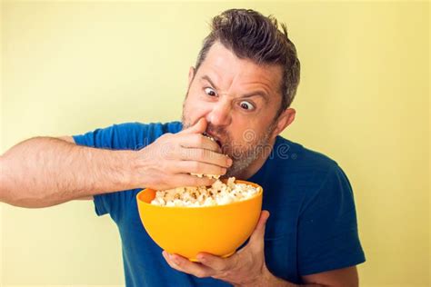 Portrait Of A Funny Man Eating Popcorn Isolated Over Yellow Background