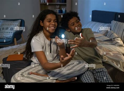 Cheerful African American Siblings Sitting On Bed And Gesturing Hands