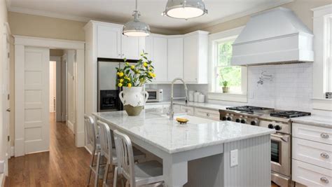 Two large industrial lamps hang from the beadboard ceiling and illuminate the massive marble topped kitchen island, supported by a large white plinth and undercounter shelves. Best Inspiration To Decorate Farmhouse Kitchen