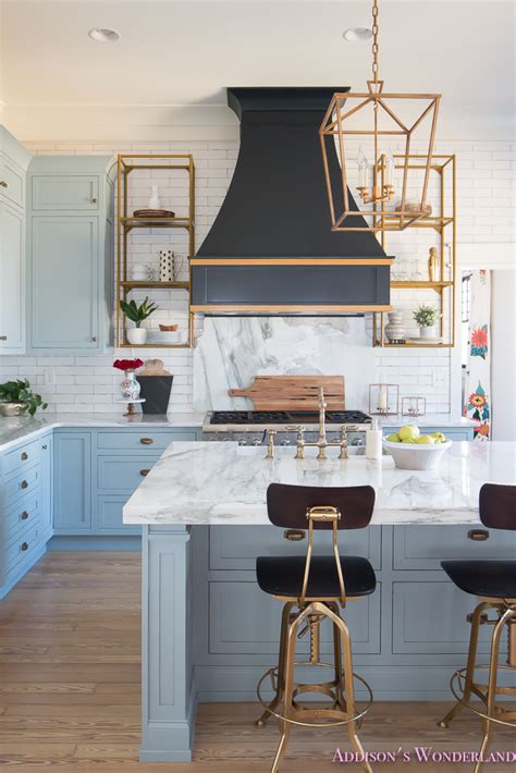 Chic kitchen features blue cabinets adorned with gold pulls paired with white marble countertops and matching backsplash. Styling Open Kitchen Shelves... - Addison's Wonderland