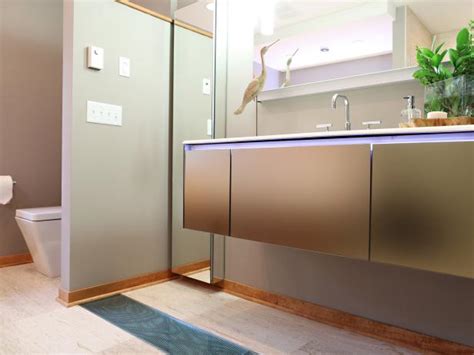 A modern eclectic bathroom with a hex tile floor, an oval tub, a wooden vanity, black fixtures and a ledge with artworks. Modern Neutral Bathroom With Wood Floor | HGTV