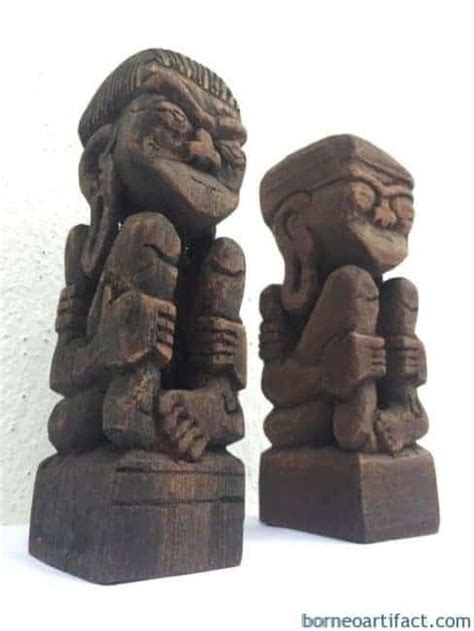 Two Carved Wooden Figures Sitting Next To Each Other