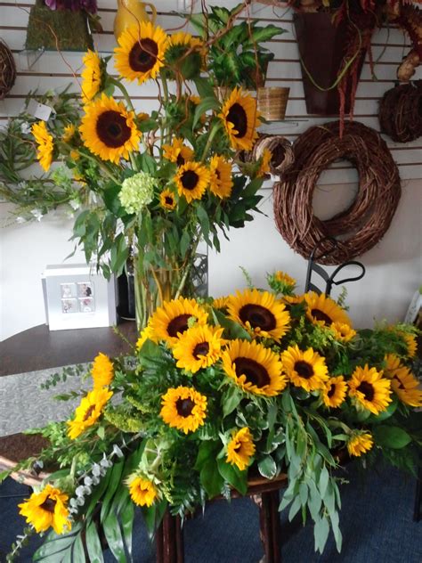 With cheery sunflowers nuzzled into a bunch of orange and coral roses, alstroemeria and purple statice in a tall vase, this striking flower arrangement captures the essence of a sunflower's sunny appearance. Sunflowers in casket spray and matching vase | Funeral ...