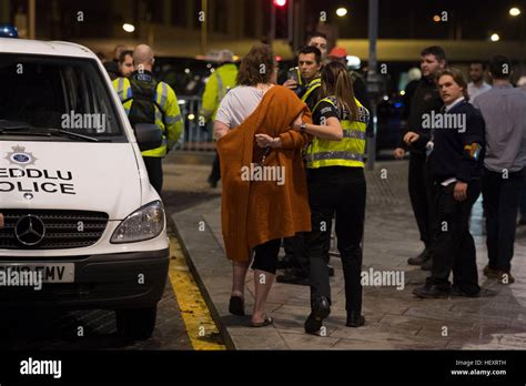 A Police Officer Escorts A Woman To A Police Van Following An Incident On St Marys Street