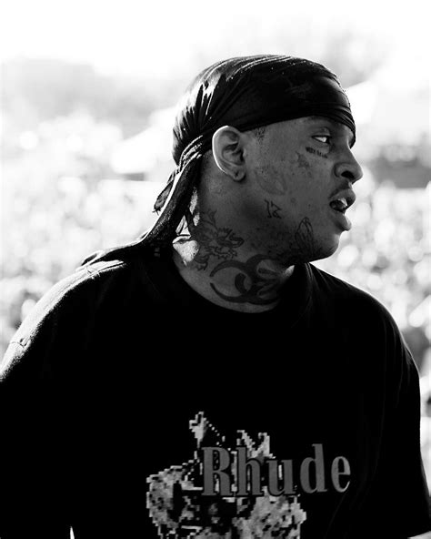 A Black And White Photo Of A Man With Tattoos On His Face Looking Off To The Side