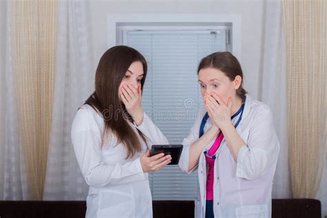 Two Female Doctors Or Nurses Look At The Tablet One Is Shocked Or Very Surprised Stock Photo