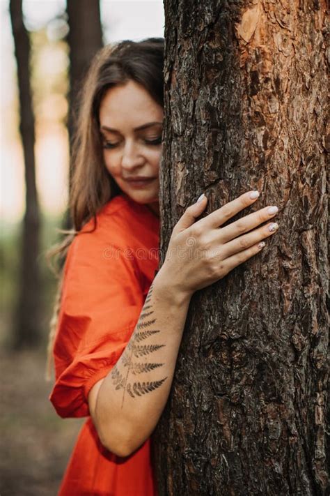 Woman With Fern Tattoo Hugging Trees And Enjoying Nature In The Pine