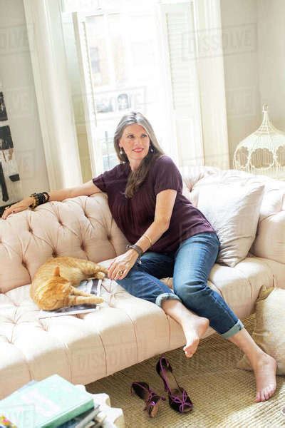 Stylish Mature Woman Sitting On Sofa With Ginger Cat Stock Photo Dissolve