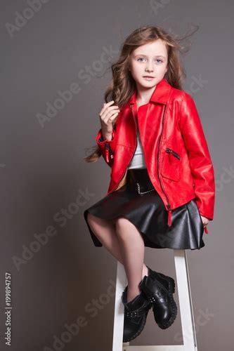 Fashion Child Girl In Red Leather Jacket And Black Skirt Posing Near