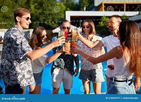 Group Of Friends Having Fun At Poolside Summer Party Clinking Glasses