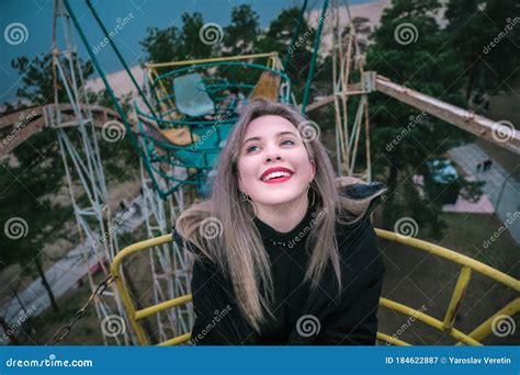Young Blonde Girl Rides On Rusty Ferris Wheel At Spring Stock Image