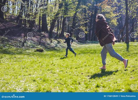 Madre Con Hijo Corriendo Por Un Parque Soleado De Primavera Imagen De