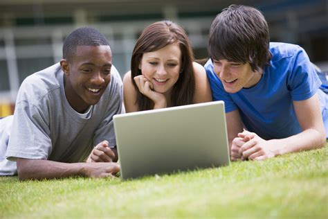 College Students Using Laptop On Campus Lawn Royalty Free Stock Image