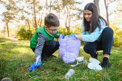 Woman Volunteer And Little Boy Picking Up The Plastic Garbage And