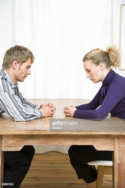 A Couple Sitting Opposite Each Other At A Table And Looking Sad High