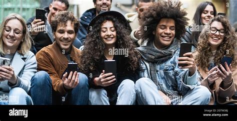 Young Multiracial Group Of Friends Using Mobile Smartphone Sitting On