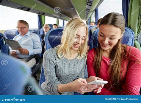Giovani Donne Felici In Bus Di Viaggio Con Lo Smartphone Immagine Stock