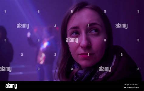 Young Woman Looking Around And Admiring Bright Laser Show In Dark Room