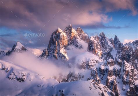 Snowy Mountain Peaks In Fog And Blue Sky With Clouds At Sunset Stock