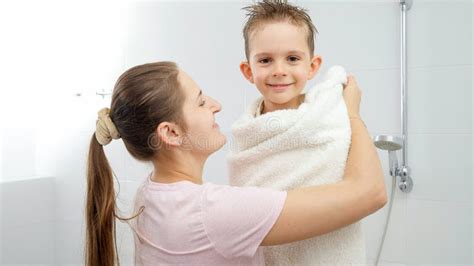Happy Smiling Mother Hugging And Covering Her Son In Bath Towel After Taking Shower Concept Of