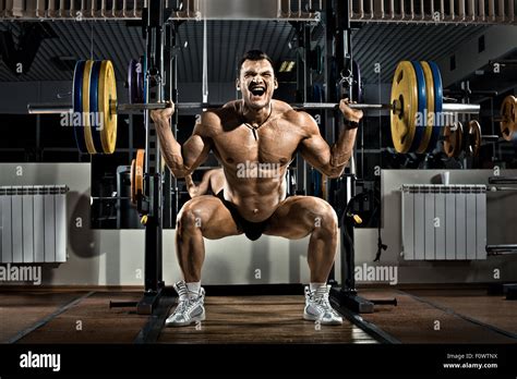 Very Brawny Guy Bodybuilder Execute Exercise Squatting With Weight In Gym Stock Photo Alamy