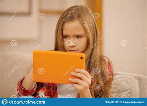 cute blonde girl with a device in hands looking involved while watching something stock image