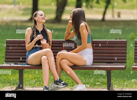 Attractive Two Women Sitting On A Park Bench On A Summer Day Stock Photo Alamy