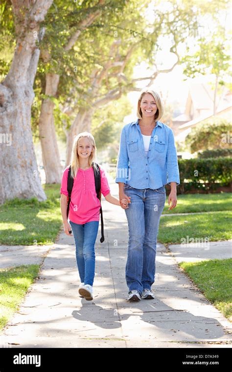 Mother And Daughter Walking To School On Suburban Street Stock Photo
