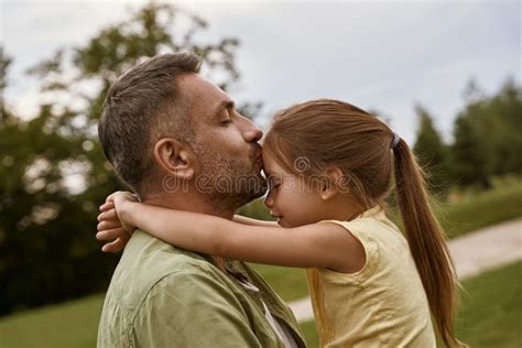 Young Loving Father Kissing His Cute Little Daughter In Forehead While Spending Time Together