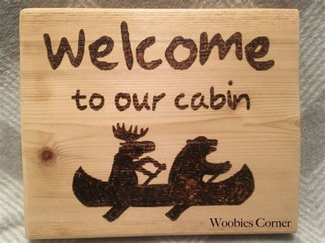 A Wooden Sign With The Words Welcome To Our Cabin And Two Moose
