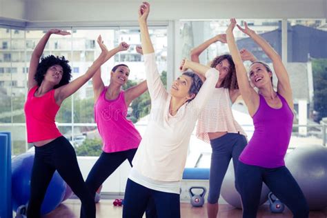 Happy Women Exercising With Arms Raised While Looking Up Stock Image