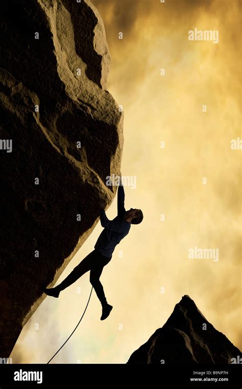 Silhouette Of Mountaineer Climbing Mountainside Side View Stock Photo
