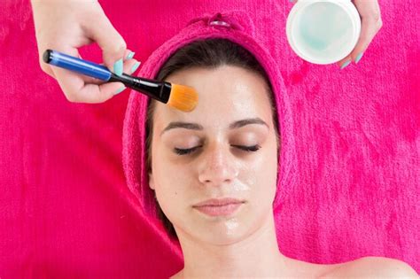 Mujer que aplica la máscara facial de arcilla tratamientos de belleza