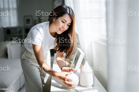 Young Asian Woman Enjoys Her Time At Home Decorating And Organising