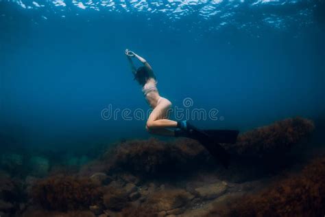 Sporty Woman Freediver With Fins Glides Underwater In Blue Sea Stock