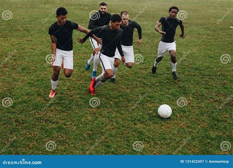 Group Of Men Playing Football On The Field Running For The Ball Soccer