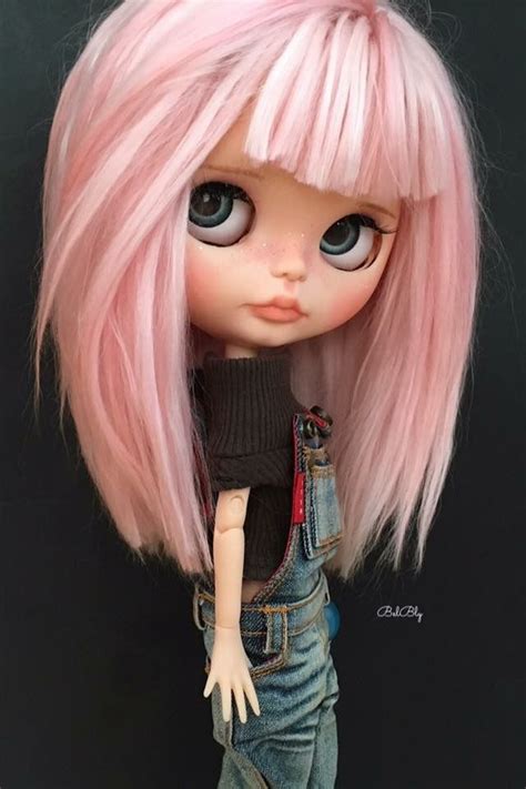 A Doll With Pink Hair Wearing Overalls And Black Shirt Standing In