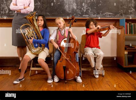 Three Students Playing Musical Instruments In A Classroom Stock Photo