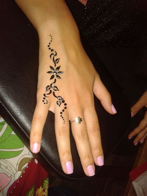 a woman s hand with a henna tattoo on her left wrist and finger