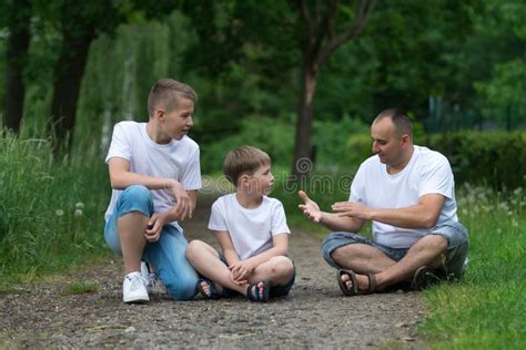 A Father With His Sons Sits On The Ground Stock Image Image Of Park