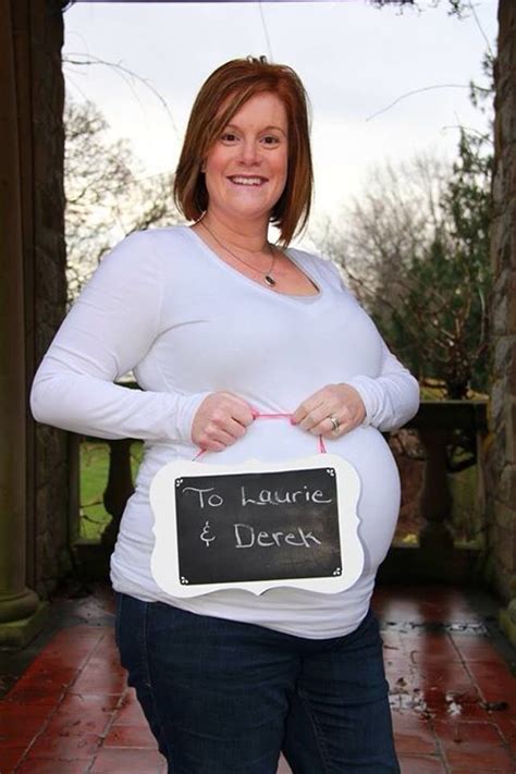a pregnant woman holding a sign that says to laurie and derek on it s belly