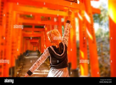 Woman Walking Beneath Red Torii Gates At Fushimi Inari Shinto Shrine