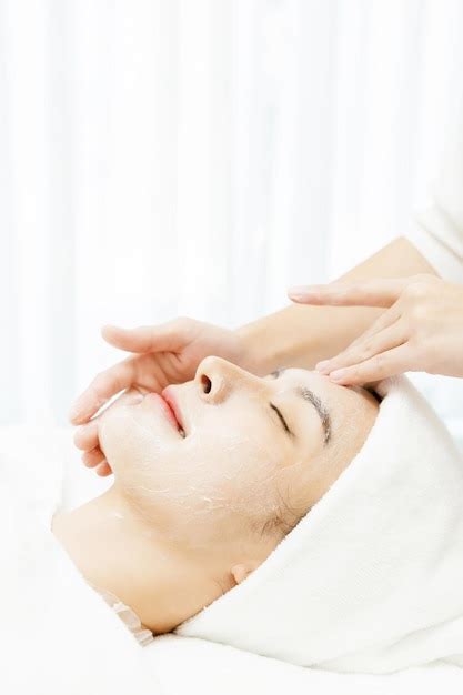 premium photo relaxed asian woman enjoying facial massage with closed eyes in beauty salon