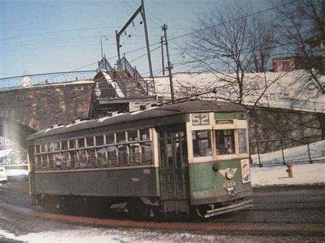 An Old Green And White Trolley Car Traveling Down The Street In Winter